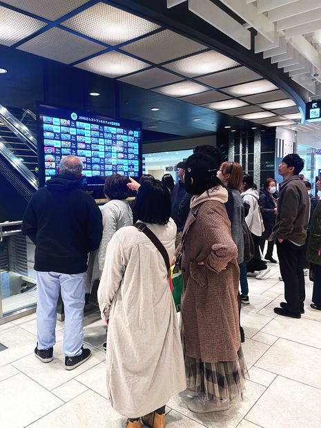 飲食店の空席情報サイネージを見る来訪者（相鉄ジョイナス）