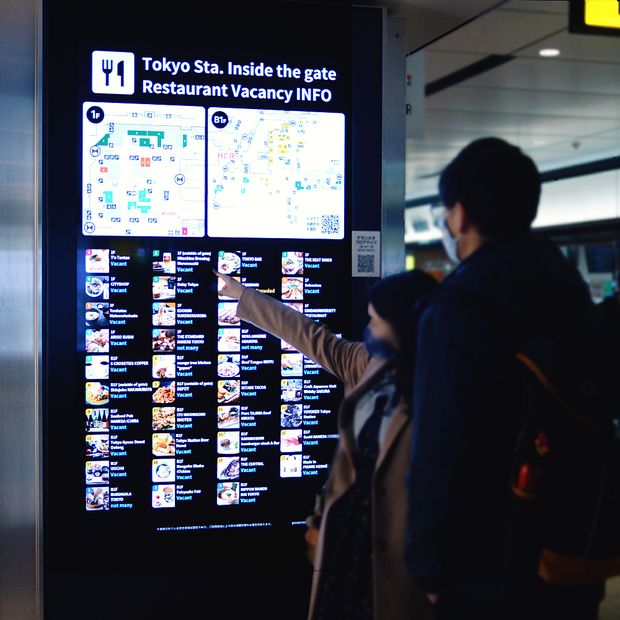 飲食店の空席情報サイネージを指さす来訪者（グランスタ東京）
