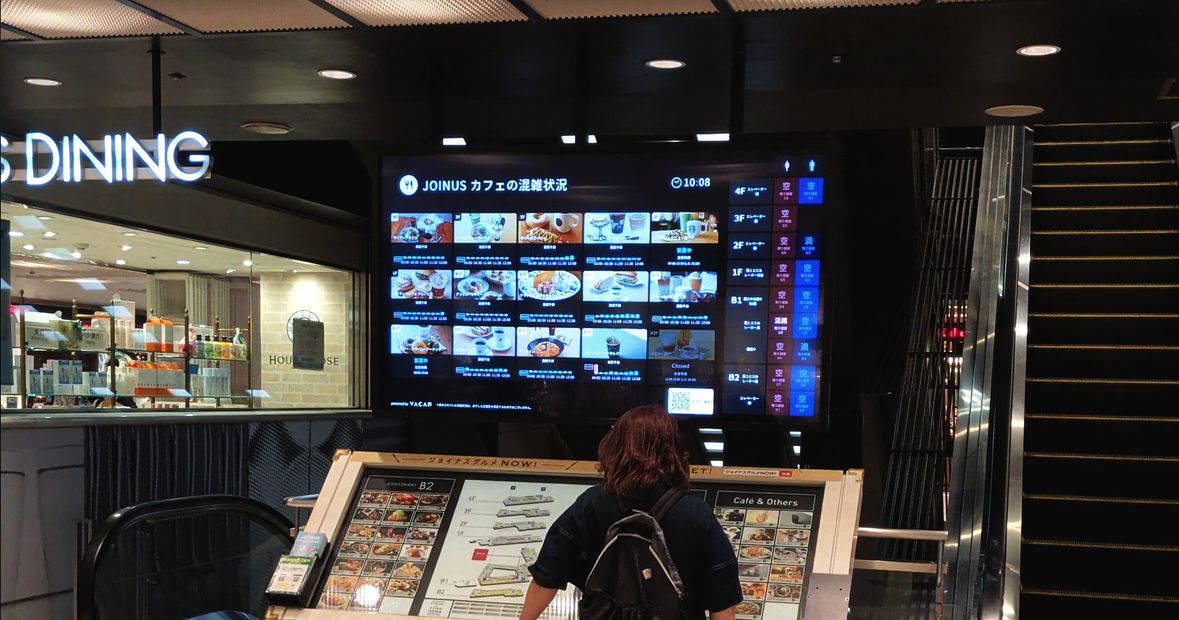 レストランフロアの空席情報サイネージを見る来訪者（相鉄ジョイナス）