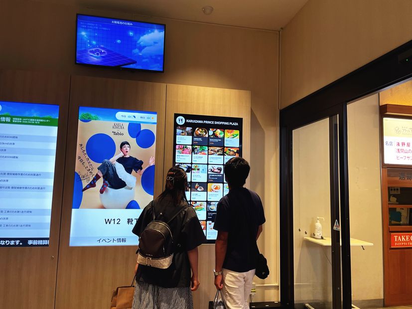 アウトレットの店舗案内サイネージを見る来訪者（軽井沢プリンスショッピングプラザ）