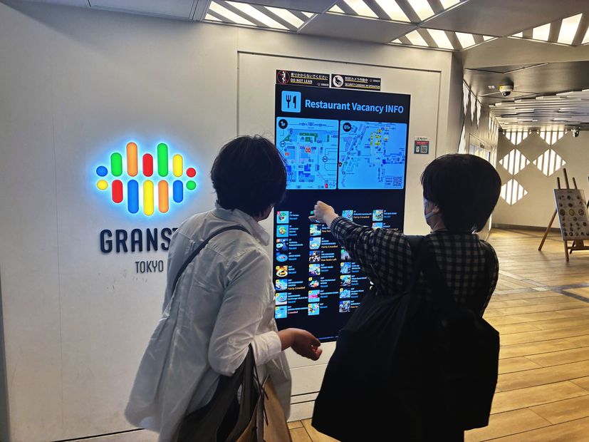 飲食店の混雑状況を指さす来訪者（グランスタ東京）