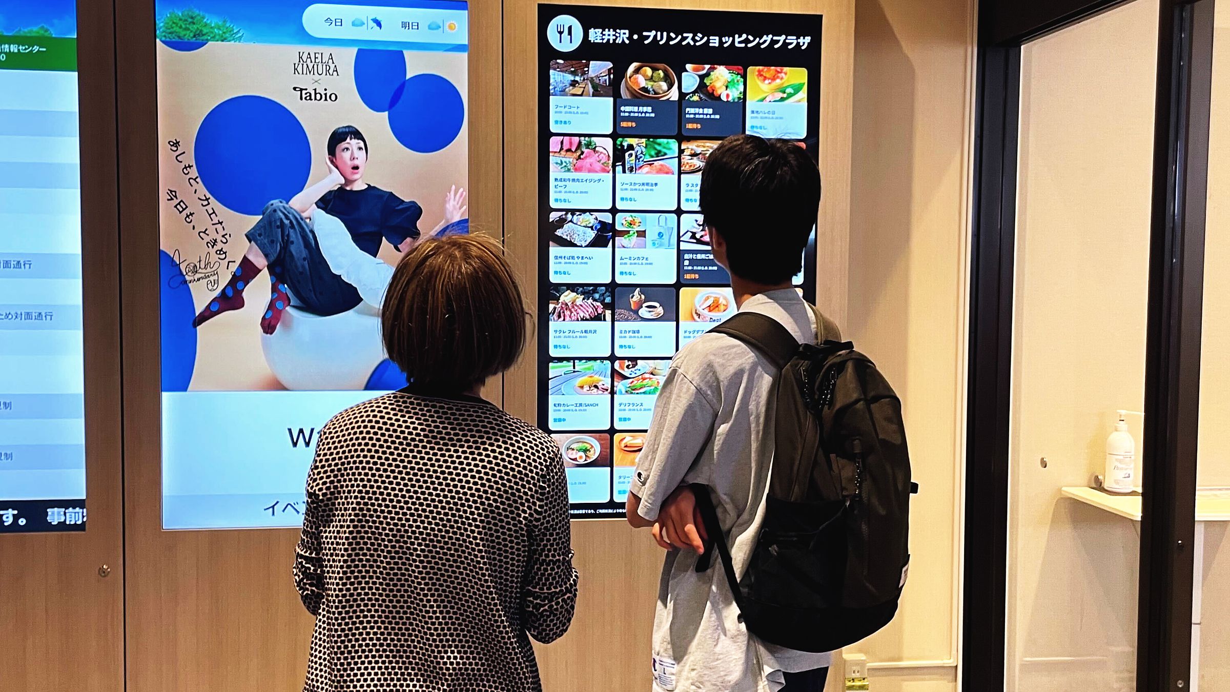 アウトレットの店舗案内サイネージを見る来訪者（軽井沢プリンスショッピングプラザ）