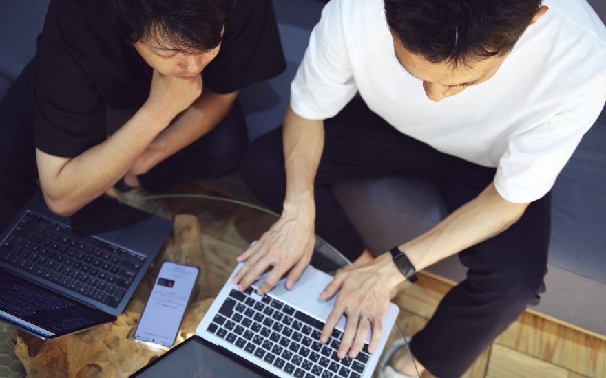 テーブルのノートPCを2人で操作する様子