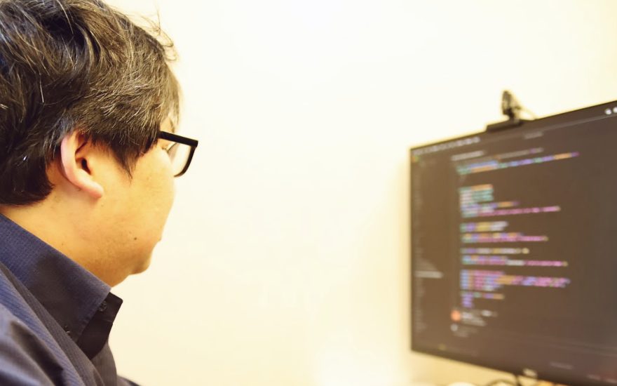 コードが表示されたモニターに向かうメンバー