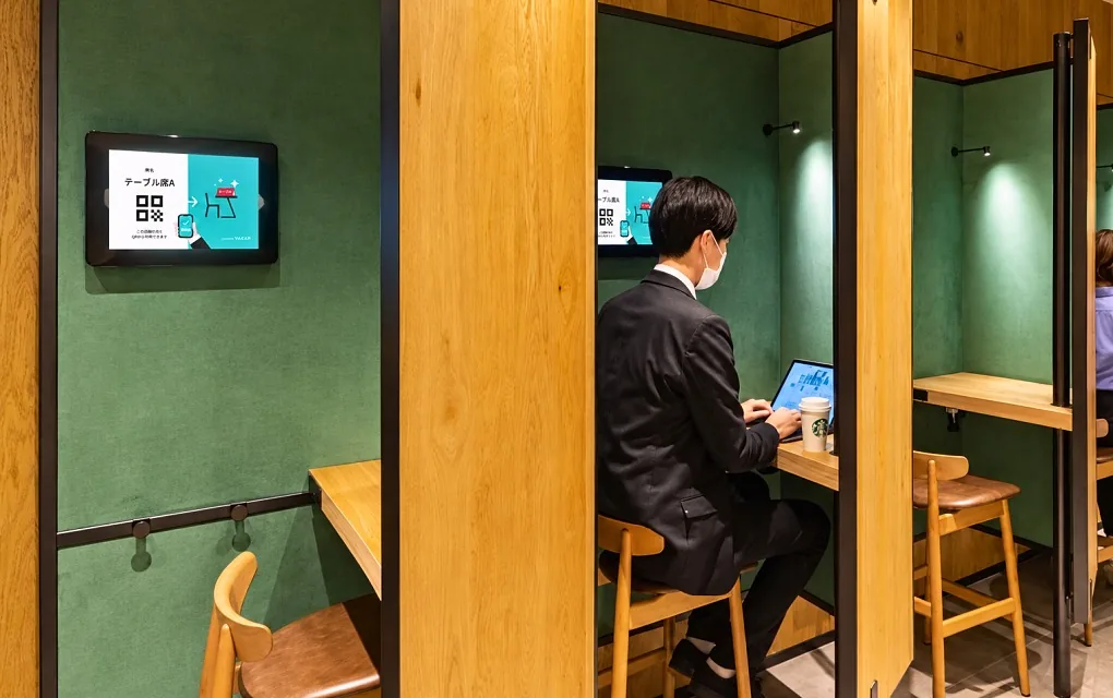 座席予約のタブレットを付けたブース席で、パソコンに向かう客（スターバックス コーヒー）