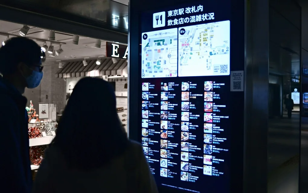 改札内の飲食店の混雑状況サイネージを見る来訪者（グランスタ東京）