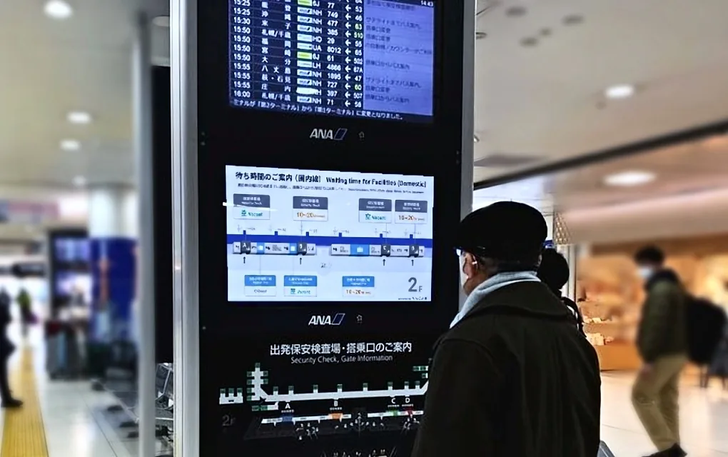 保安検査場の待ち時間を表示するサイネージを見る旅客（羽田空港）