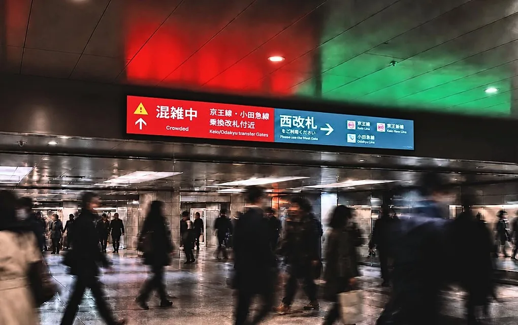 駅の通路で混雑を知らせる表示と、行き交う人